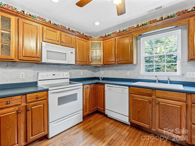 kitchen with light hardwood / wood-style flooring, tasteful backsplash, white appliances, ceiling fan, and sink