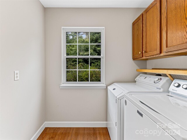 clothes washing area with cabinets, independent washer and dryer, and wood-type flooring