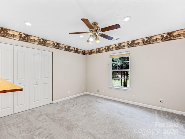 unfurnished bedroom featuring ceiling fan, light carpet, and a closet