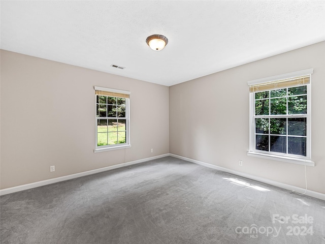 carpeted empty room featuring a textured ceiling