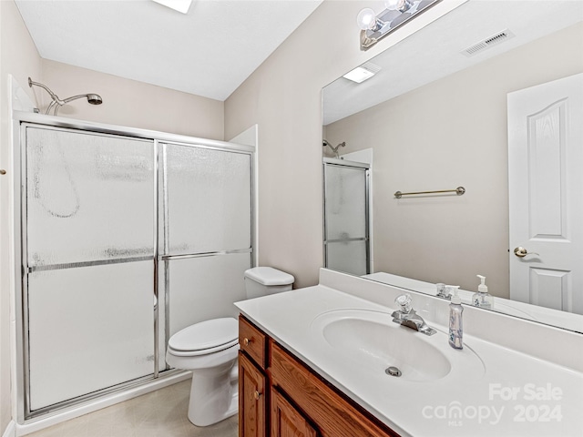 bathroom with vanity, a shower with shower door, and toilet