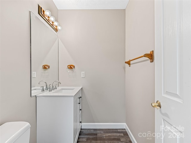 bathroom with toilet, hardwood / wood-style flooring, and vanity