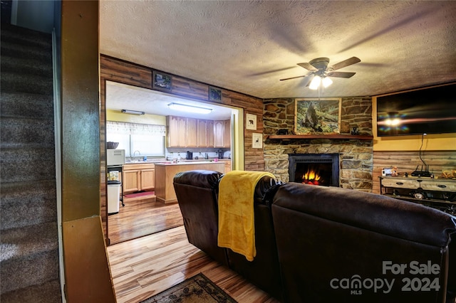 living room featuring sink, ceiling fan, light wood-type flooring, a textured ceiling, and log walls