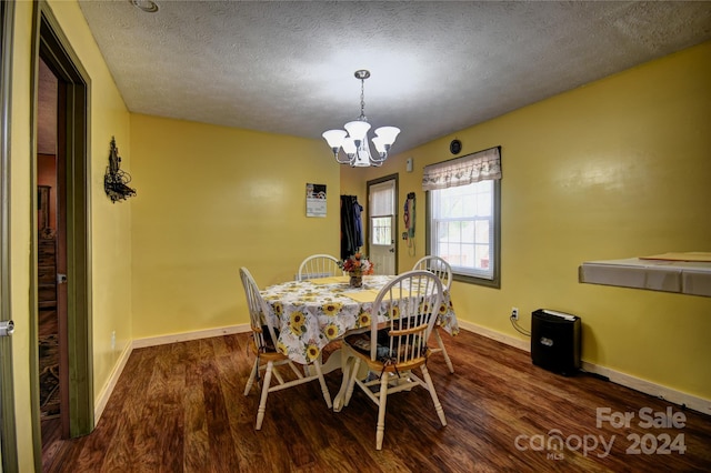 dining space featuring a textured ceiling, dark hardwood / wood-style floors, and an inviting chandelier