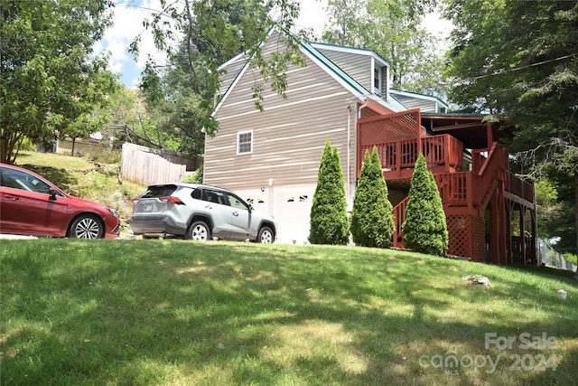 view of side of property with a yard, a deck, and a garage