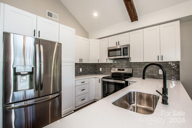 kitchen featuring white cabinetry, sink, vaulted ceiling with beams, backsplash, and appliances with stainless steel finishes