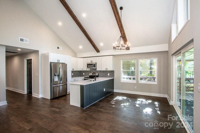 kitchen featuring kitchen peninsula, stainless steel appliances, pendant lighting, high vaulted ceiling, and white cabinetry