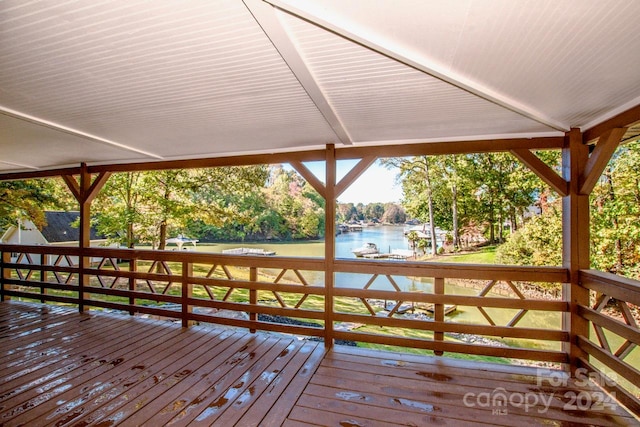 wooden terrace featuring a water view and a yard