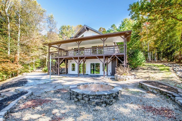 rear view of property featuring a fire pit, a patio area, and a wooden deck