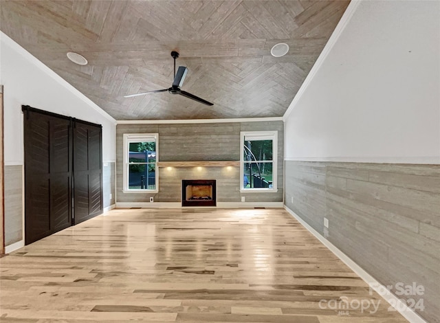 unfurnished living room featuring light wood-type flooring, lofted ceiling, ceiling fan, and ornamental molding