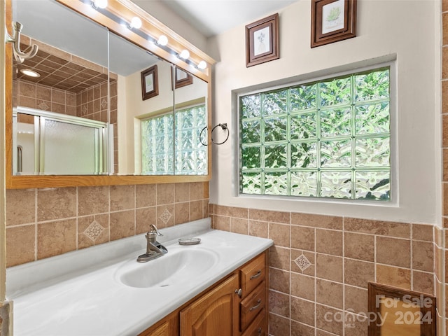 bathroom with tile walls, vanity, and an enclosed shower