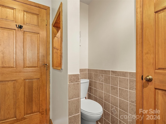 bathroom with tile walls and toilet