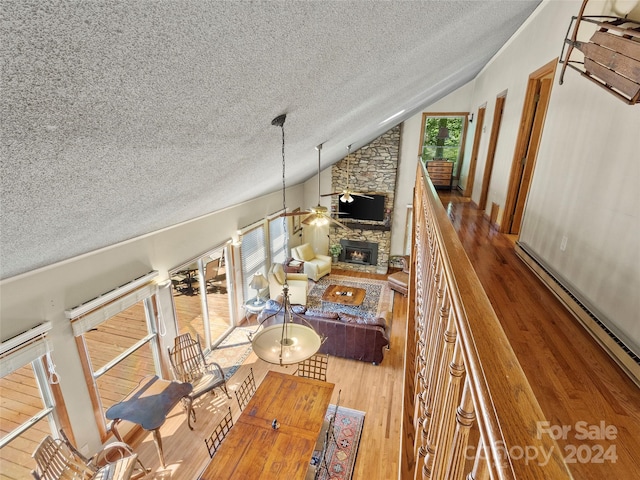 unfurnished living room with a fireplace, hardwood / wood-style flooring, a baseboard radiator, and lofted ceiling