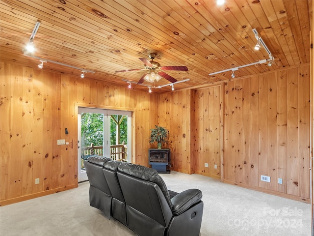 living room with a wood stove, ceiling fan, rail lighting, light carpet, and wood ceiling