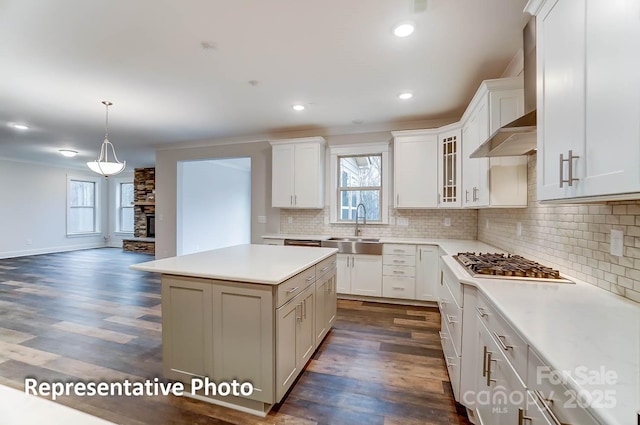 kitchen featuring stainless steel gas stovetop, dark hardwood / wood-style floors, sink, white cabinets, and a center island