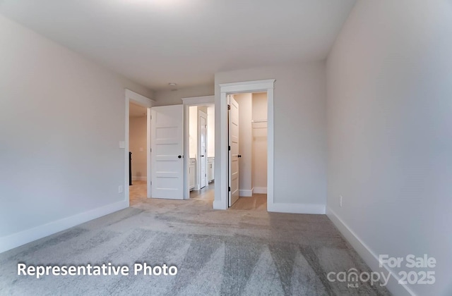 unfurnished bedroom featuring a spacious closet, a closet, and light carpet