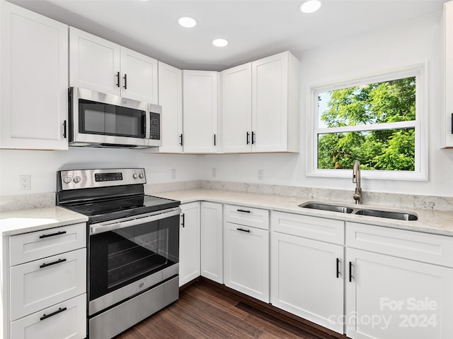 kitchen with white cabinetry, sink, light stone counters, dark hardwood / wood-style floors, and appliances with stainless steel finishes