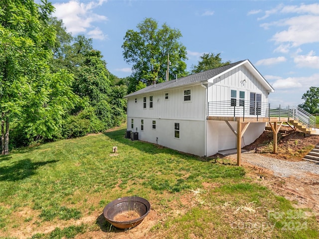 view of home's exterior with a wooden deck, central AC, an outdoor fire pit, a garage, and a lawn