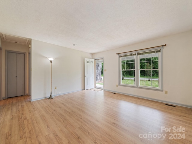 spare room featuring light hardwood / wood-style floors and a textured ceiling