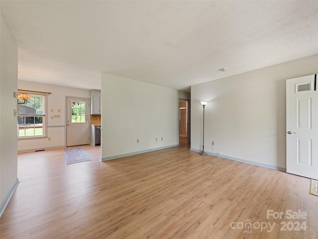 empty room with light hardwood / wood-style flooring, a chandelier, and a textured ceiling