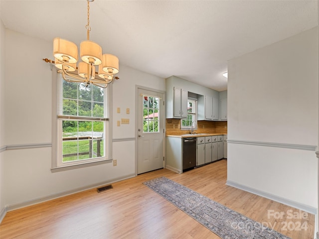 kitchen with pendant lighting, sink, stainless steel dishwasher, tasteful backsplash, and a notable chandelier