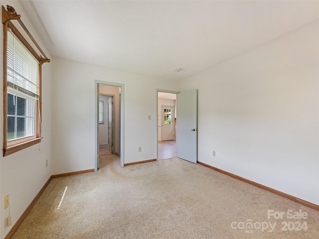 unfurnished bedroom featuring light carpet and multiple windows