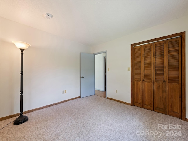 unfurnished bedroom featuring light carpet and a closet