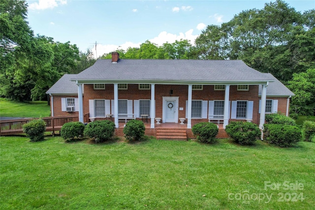 view of front facade with a front lawn, cooling unit, and covered porch