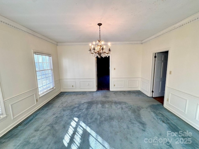 carpeted spare room featuring ornamental molding and a chandelier