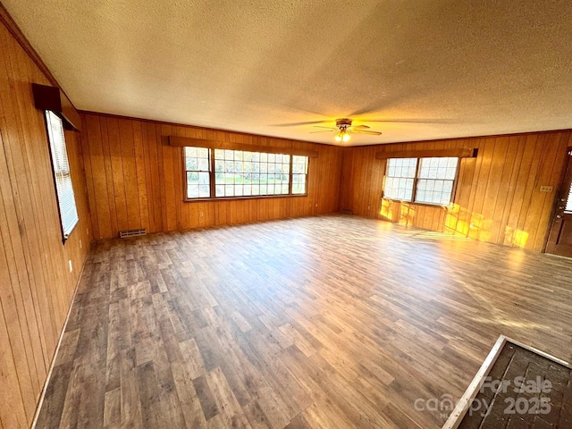 unfurnished living room with hardwood / wood-style flooring, a textured ceiling, and a wealth of natural light