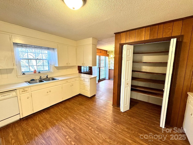 kitchen featuring white cabinetry, wood-type flooring, sink, white dishwasher, and a textured ceiling