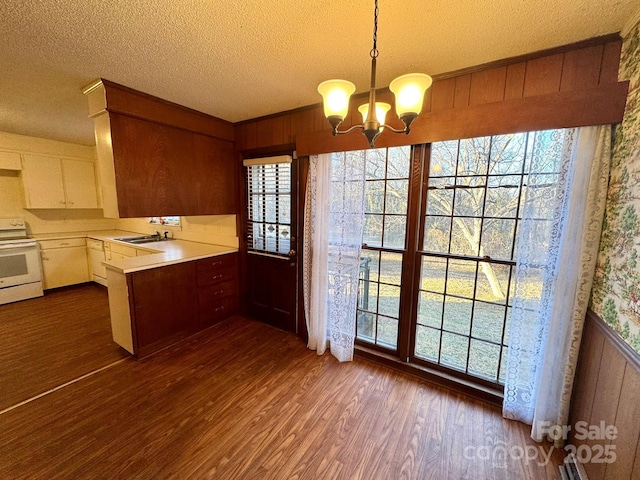 kitchen with sink, dark wood-type flooring, white range with electric stovetop, white cabinets, and decorative light fixtures