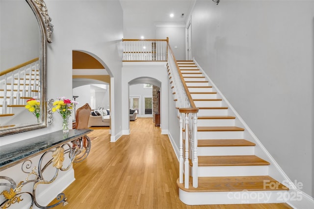 foyer featuring ornamental molding, a towering ceiling, and light hardwood / wood-style floors