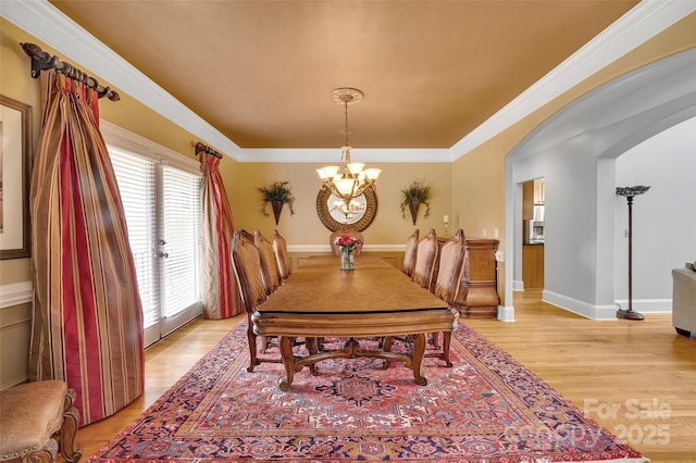 dining space with ornamental molding, an inviting chandelier, and light hardwood / wood-style floors