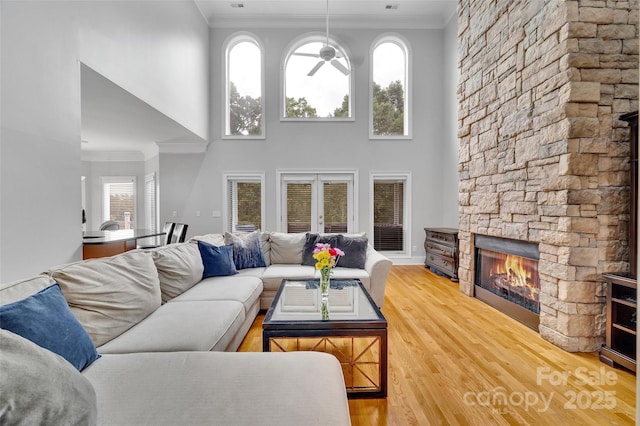 living room featuring crown molding, hardwood / wood-style floors, a high ceiling, a fireplace, and french doors