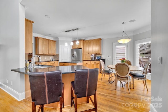 kitchen with stainless steel fridge, decorative light fixtures, sink, and kitchen peninsula