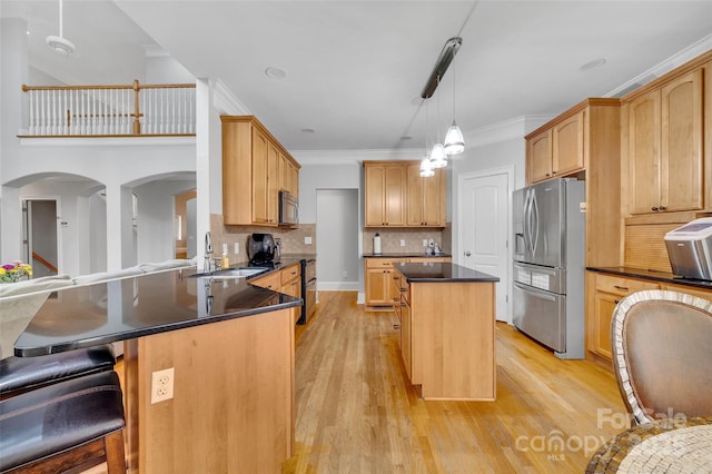 kitchen with stainless steel appliances, light hardwood / wood-style floors, decorative backsplash, a kitchen island, and decorative light fixtures