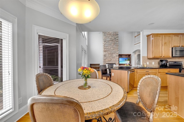 dining area with ornamental molding, light hardwood / wood-style floors, and sink