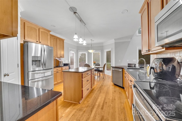 kitchen featuring sink, crown molding, hanging light fixtures, a kitchen island, and stainless steel appliances