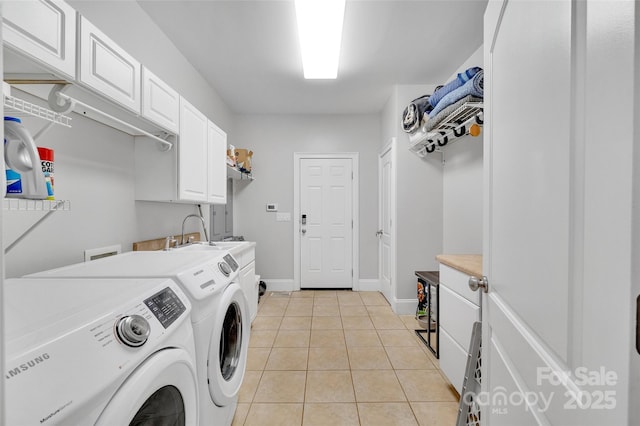 clothes washing area with cabinets, washing machine and dryer, and light tile patterned floors