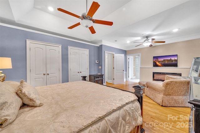 bedroom with hardwood / wood-style floors, a tray ceiling, ornamental molding, and ceiling fan