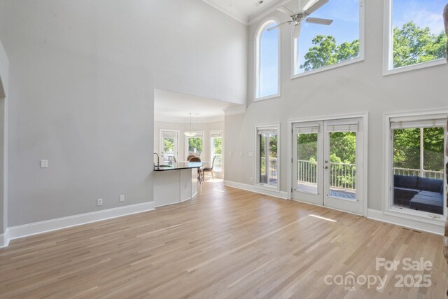 122 Long Cove Ln, Mooresville, NC 28117 - unfurnished living room with crown molding, a high ceiling, light wood-style floors, a ceiling fan, and a healthy amount of sunlight