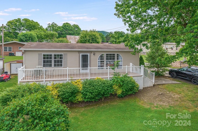 view of front of house featuring a front yard, a wooden deck, and a storage unit