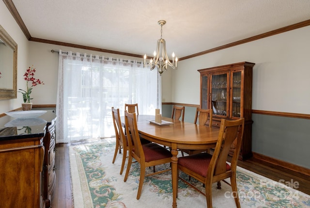 dining area featuring dark wood-type flooring, an inviting chandelier, ornamental molding, and a textured ceiling