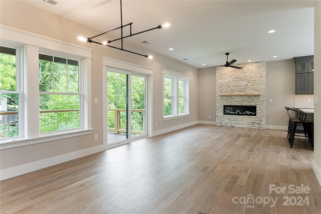 unfurnished living room featuring a fireplace, ceiling fan, light hardwood / wood-style floors, and plenty of natural light