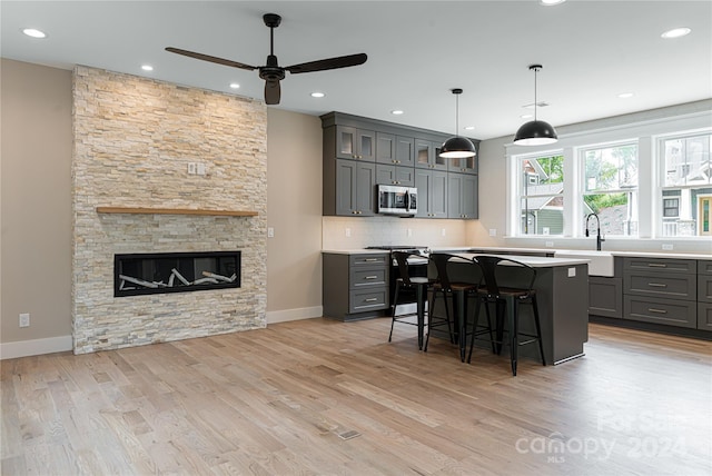 kitchen featuring appliances with stainless steel finishes, a breakfast bar, a fireplace, a kitchen island, and sink