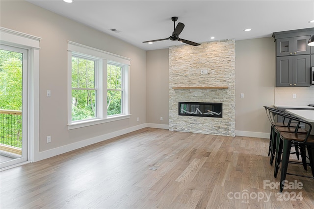 living room featuring a fireplace, ceiling fan, and light hardwood / wood-style floors