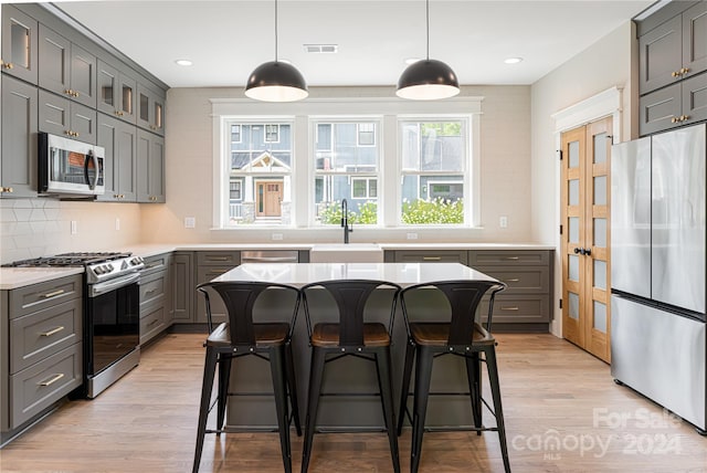 kitchen featuring sink, stainless steel appliances, pendant lighting, and a center island