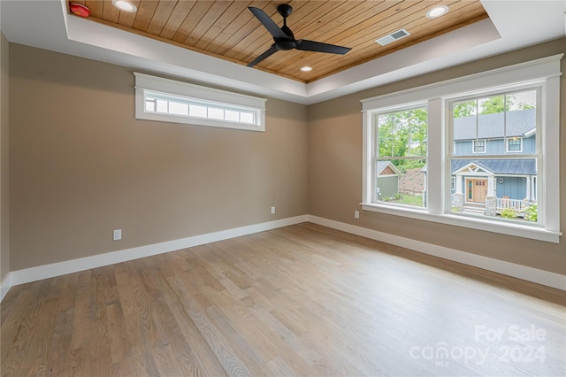 spare room with light wood-type flooring, a healthy amount of sunlight, a raised ceiling, and wooden ceiling