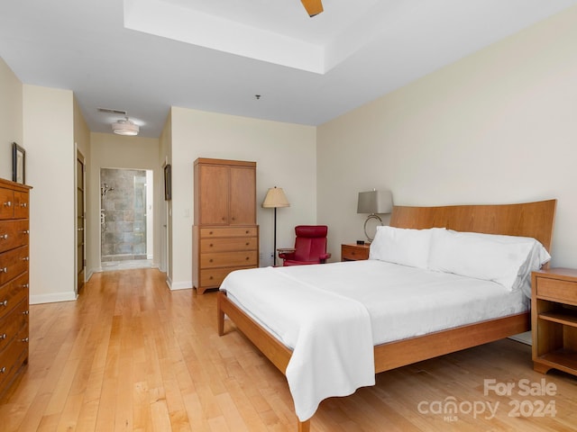 bedroom featuring ceiling fan, light wood-type flooring, and ensuite bath